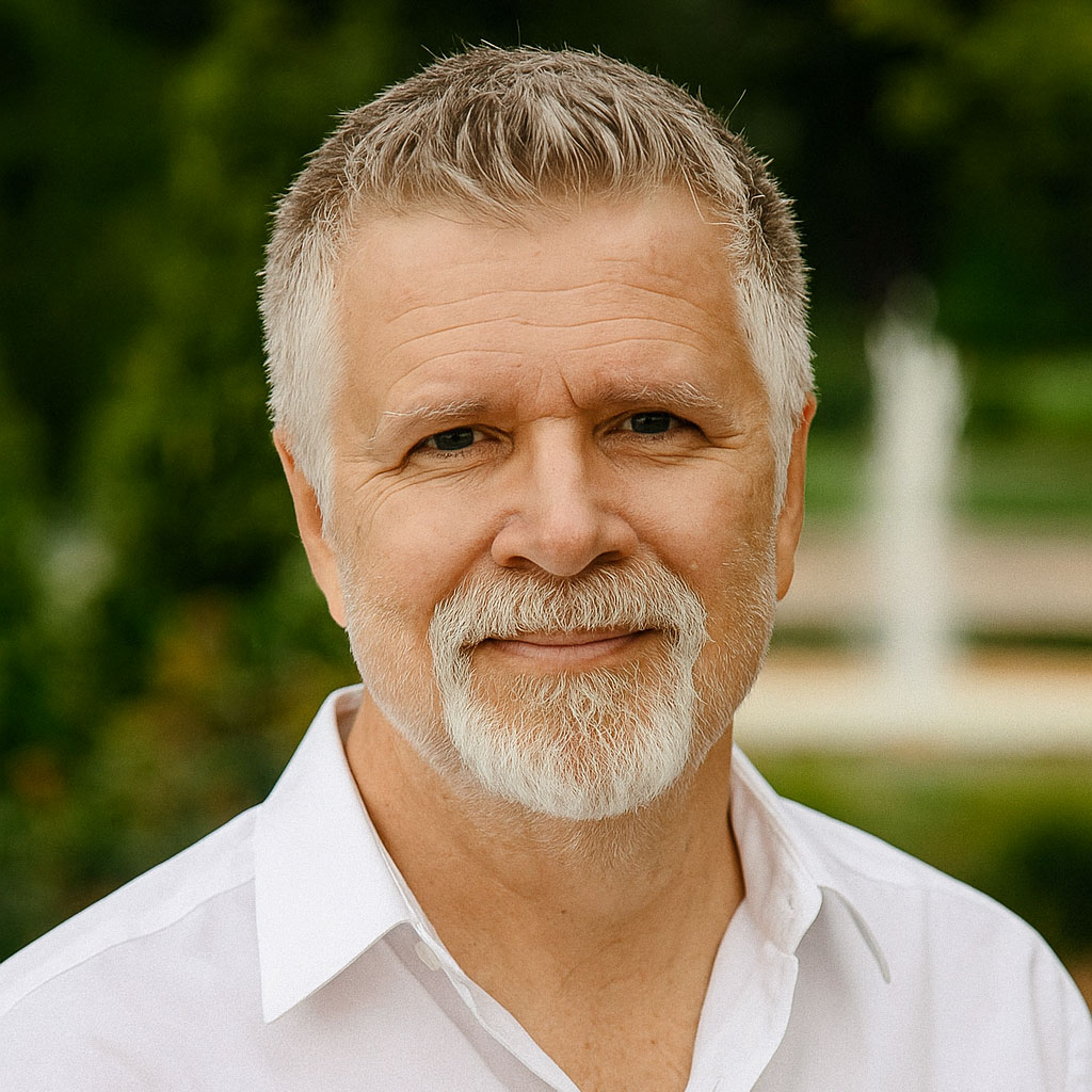 Portrait of Jeff Evans, author of the Bella & Mandy children’s book series, smiling outdoors in a white shirt with a neatly trimmed white beard and short gray hair.